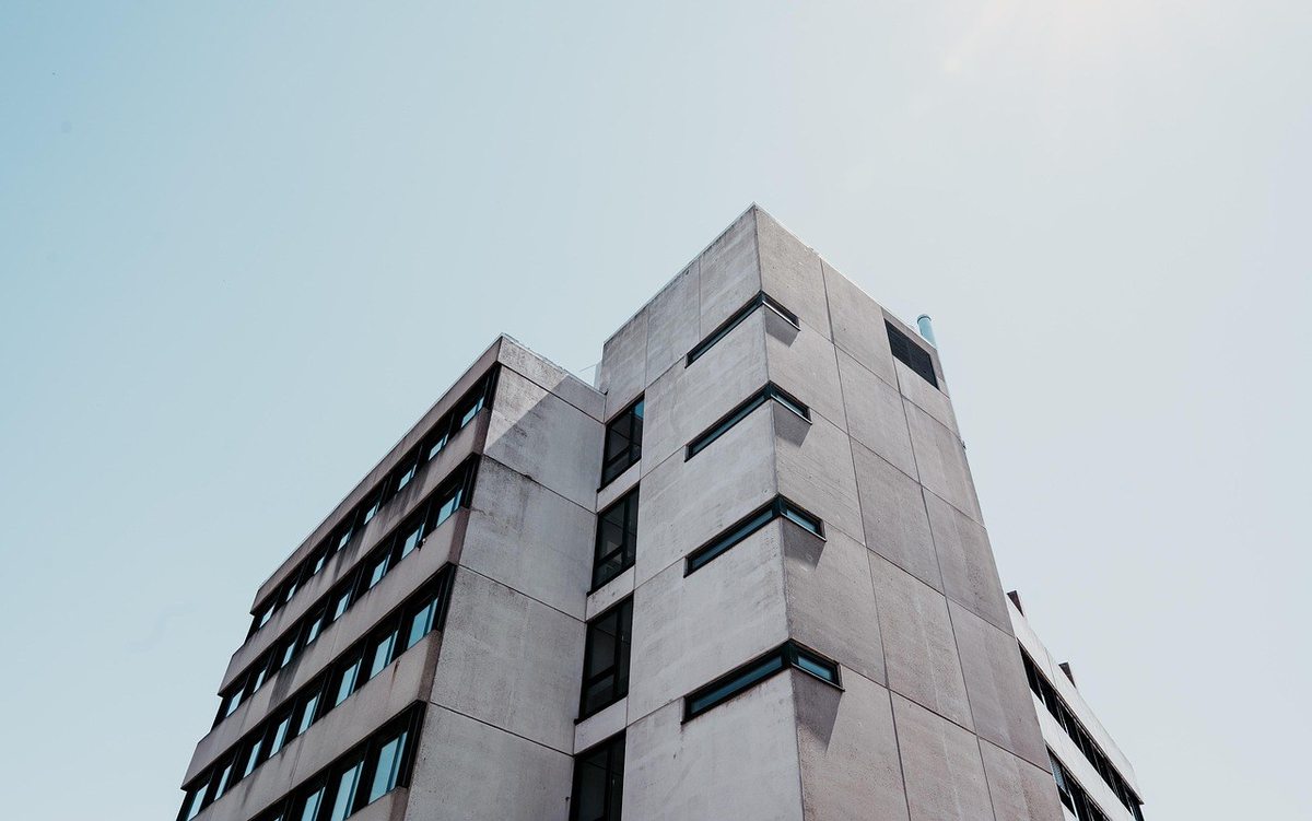 Immeuble gris avec des fenêtres, vu d'un angle droit contre un ciel bleu Immeuble gris avec des fenêtres, vu d'un angle droit contre un ciel bleu